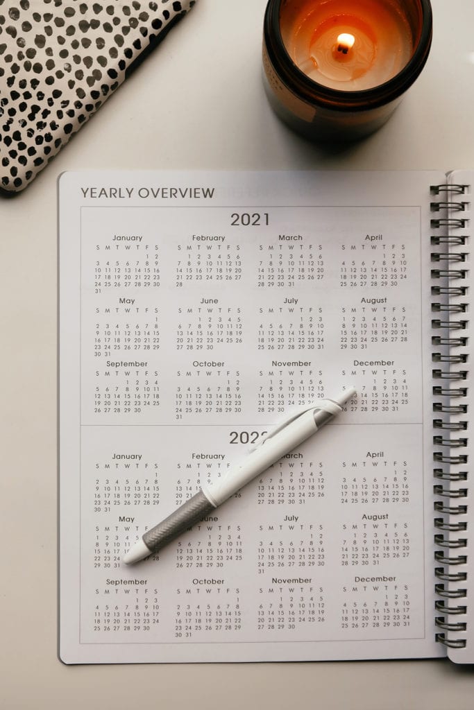 What does self care looks like in 2021. New Resolutions and routines |What does self care looks like in 2021 | Self Care Ideas by popular LA lifestyle blog, Tea Cups and Tulips: image of a grey planner, white pen, burning candle, and a smartphone with a black and white dot phone case. 